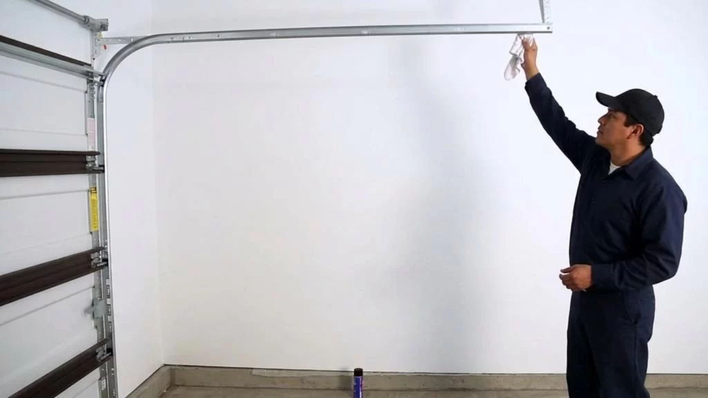 A technician cleaning garage door track to improve performance and avoid costly repairs