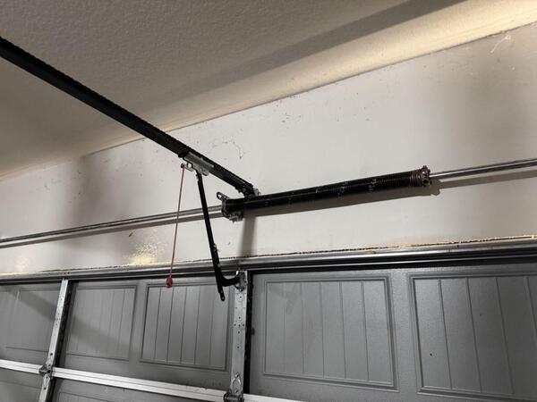 Garage door spring mechanism and track system above a closed garage door, illustrating the repair process for a malfunctioning garage door in Houston, TX.