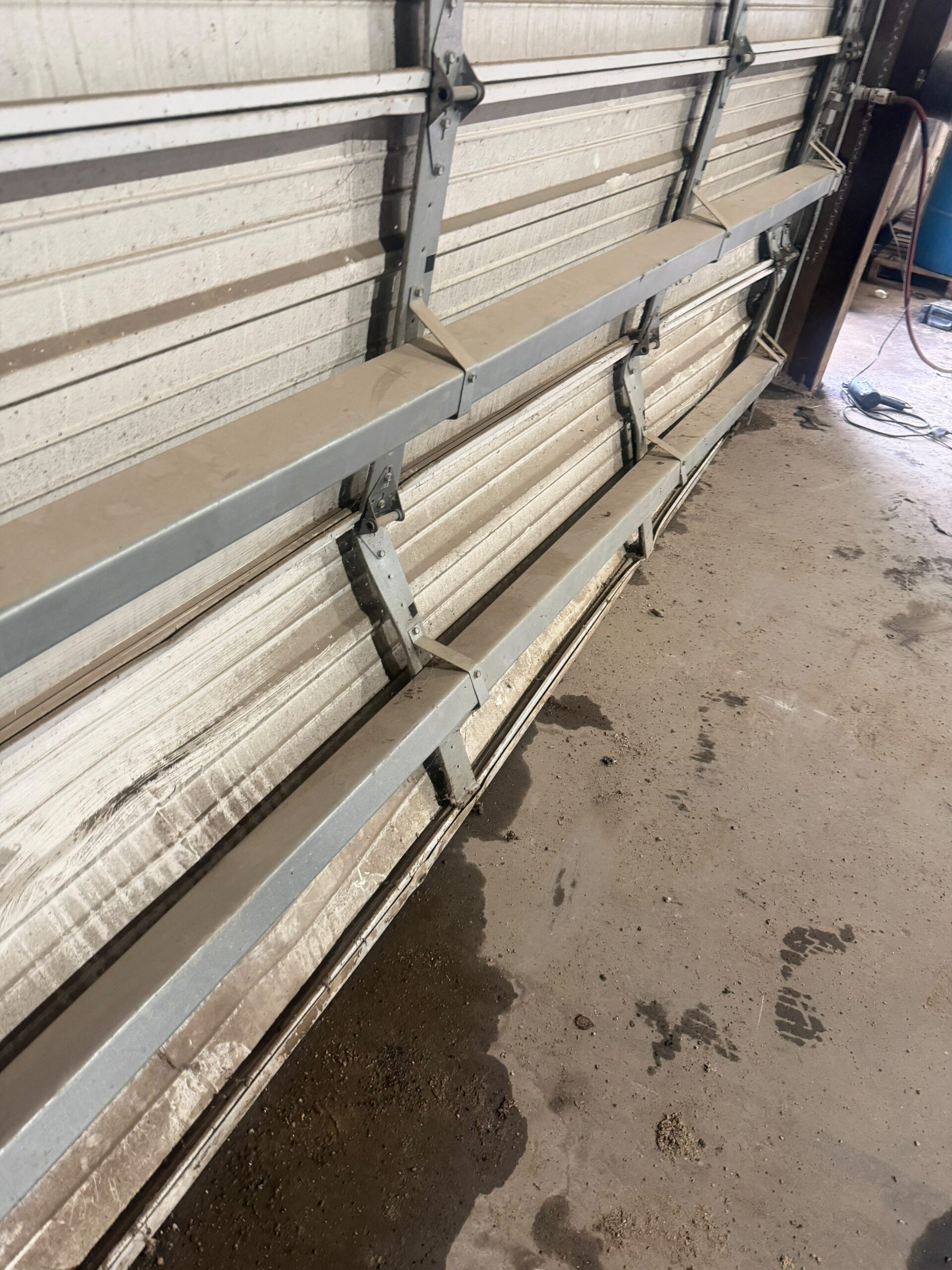 Commercial garage door repair on a heavy-duty overhead door with visible panel damage