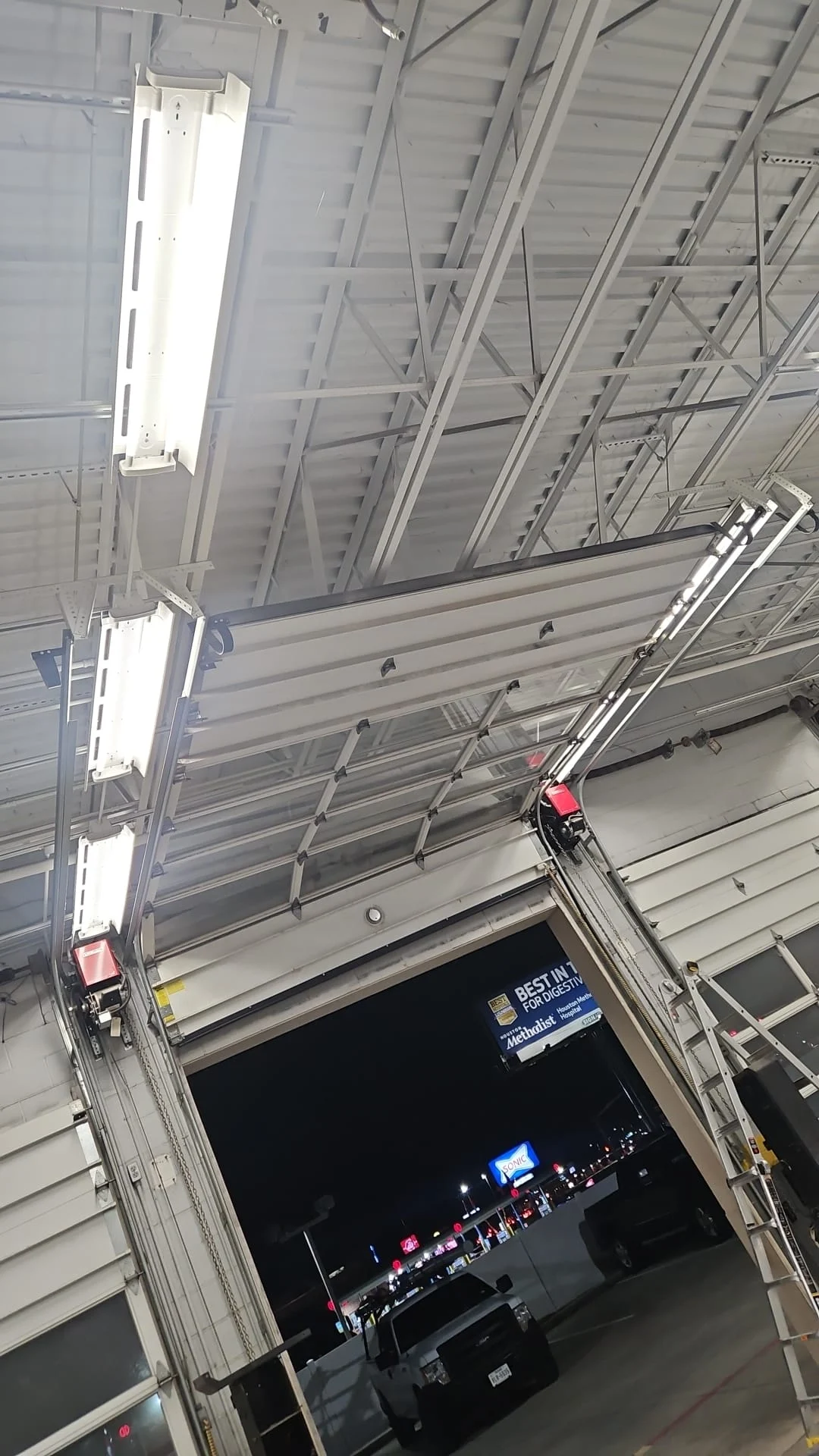 Commercial garage door repair featuring a full-view aluminum overhead door at an automotive service center.