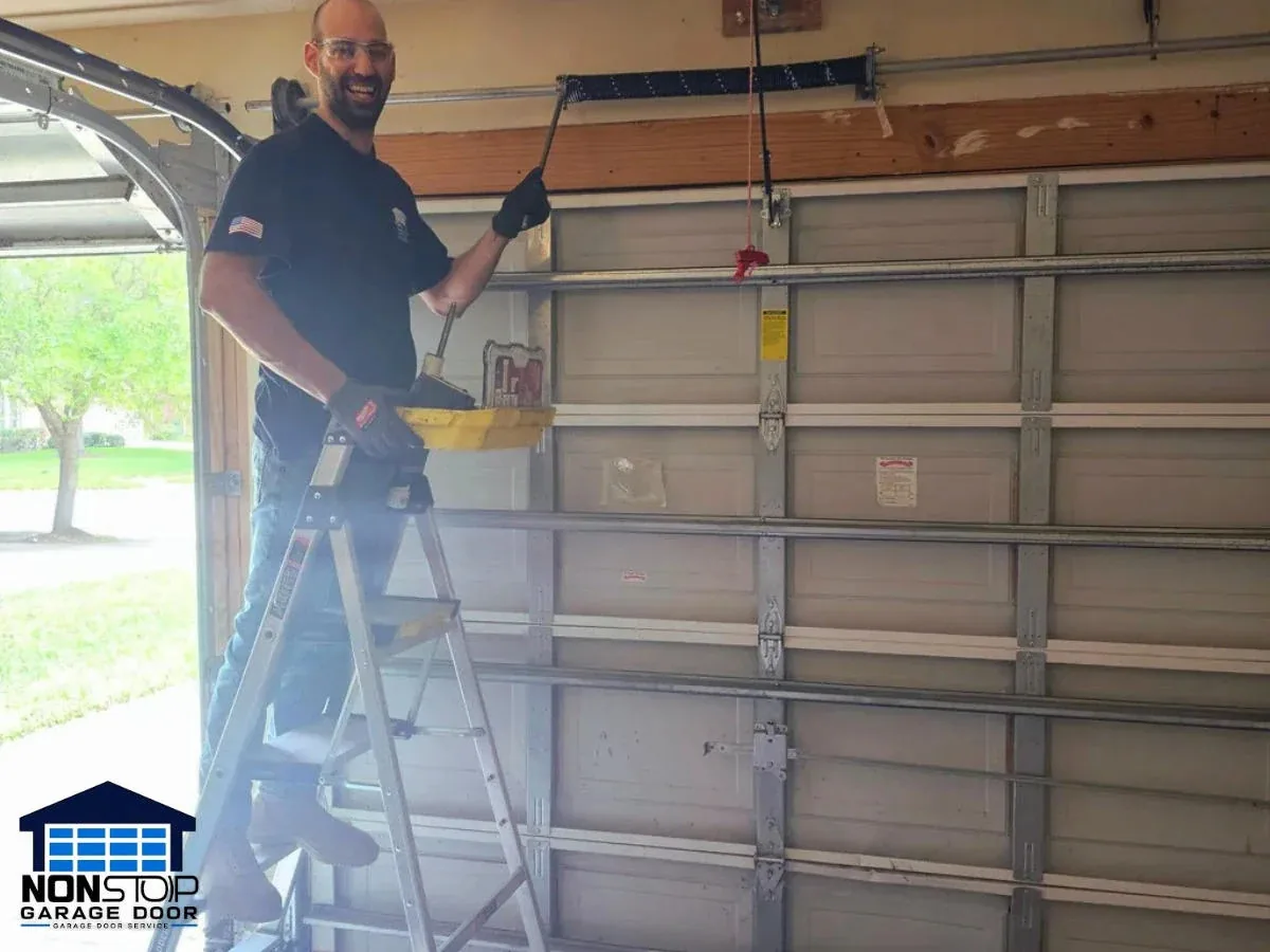 Garage door technician working on a torsion spring system in Houston TX by Non Stop Garage Door