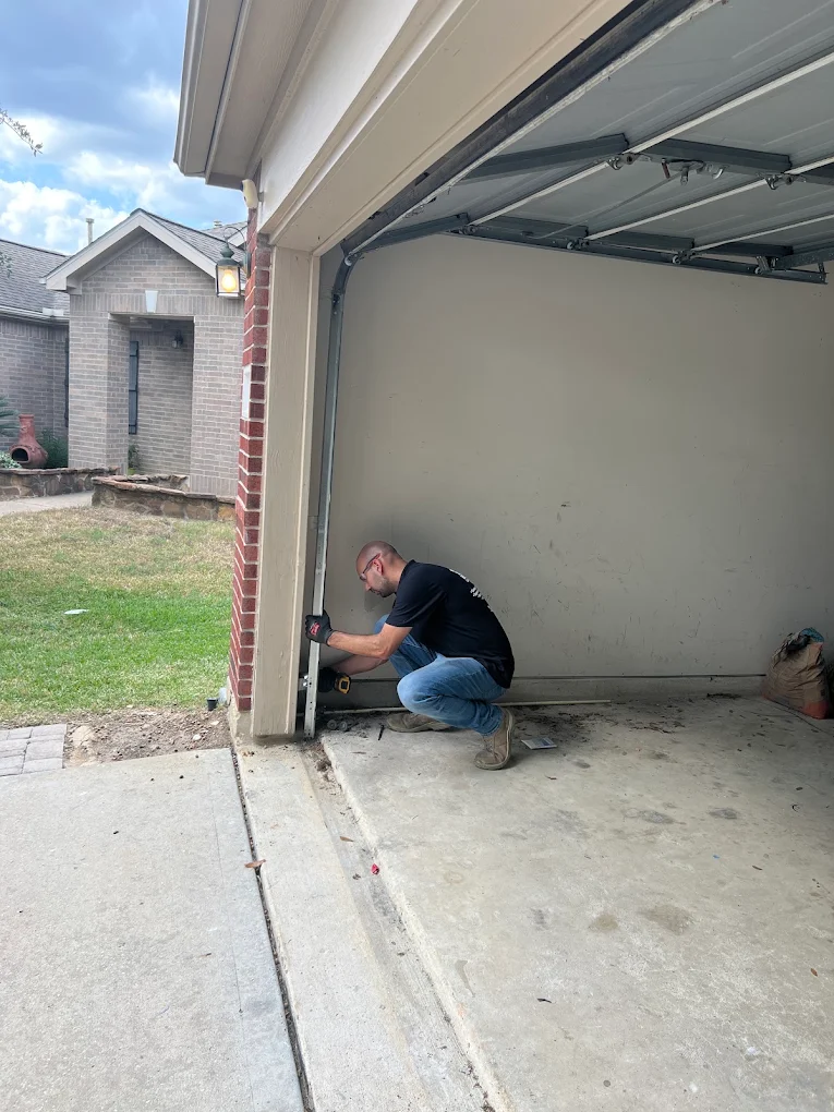 Non Stop Garage Door technician inspecting garage door track and lower hardware in Houston TX