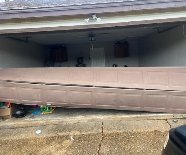 Garage door off track and tilted, obstructing garage entrance, showcasing potential damage and need for repair services from Non Stop Garage Door.